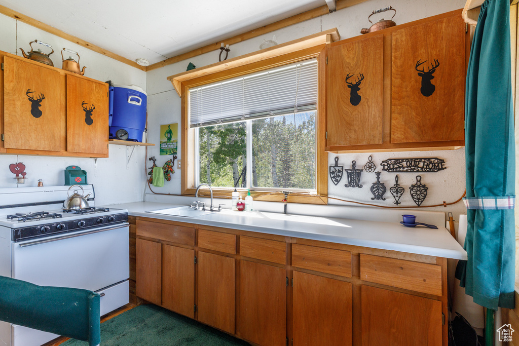Kitchen featuring white gas range, light countertops, brown cabinets, and open shelves