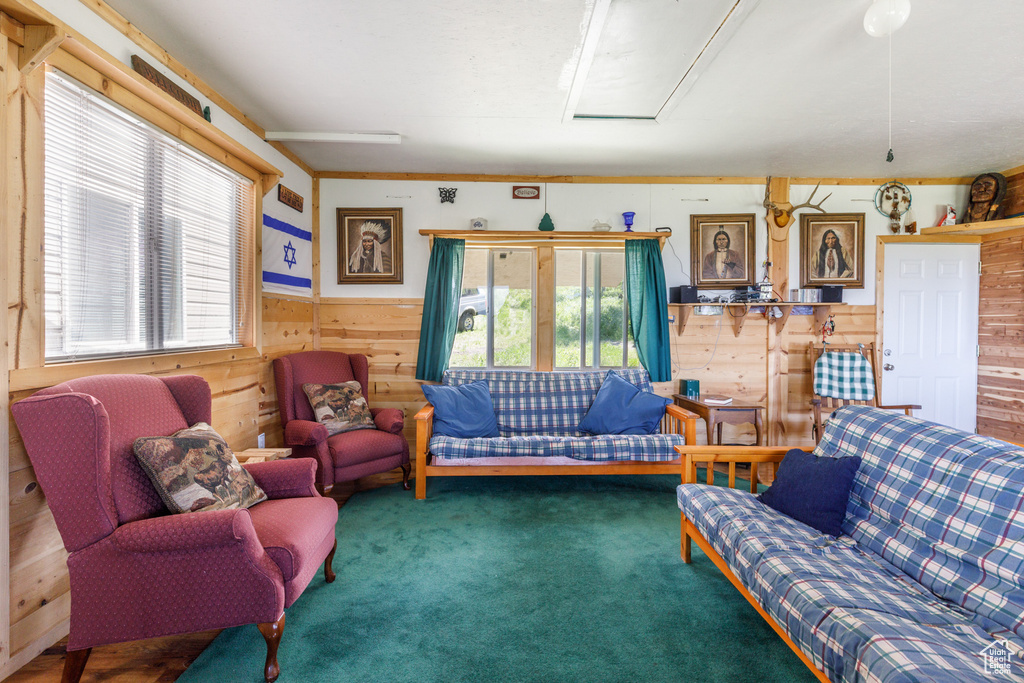 Carpeted living room with wood walls, a wainscoted wall, and attic access