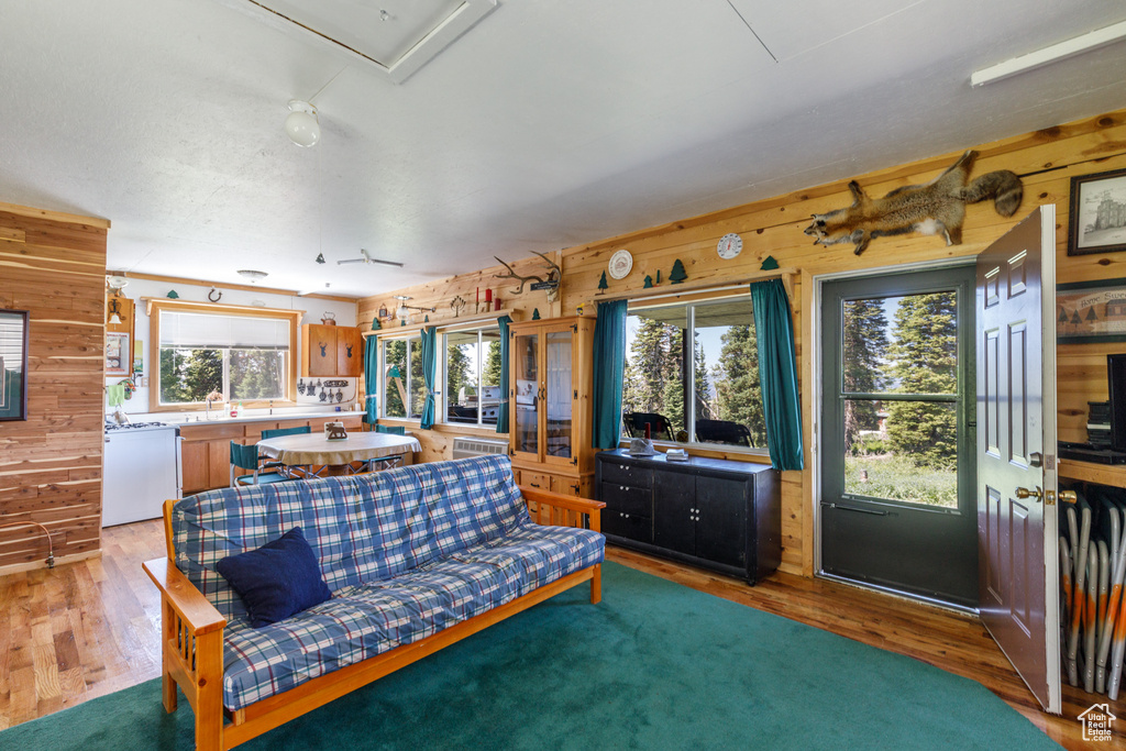 Living area with wood walls, light wood-style flooring, and attic access