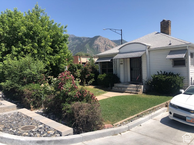 View of front of house with a mountain view, a chimney, and a front yard