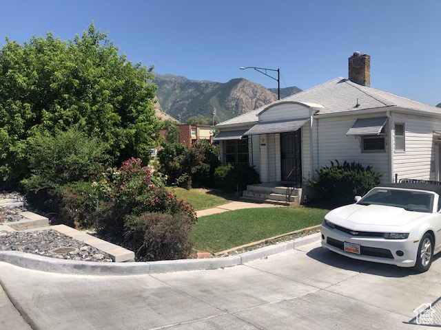 View of front of home featuring a chimney, a mountain view, and a front lawn