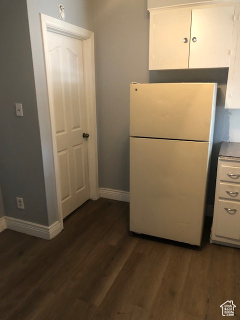 Kitchen with freestanding refrigerator, white cabinetry, and dark wood-style flooring