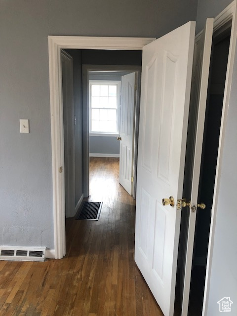 Corridor with dark wood-style floors and baseboards