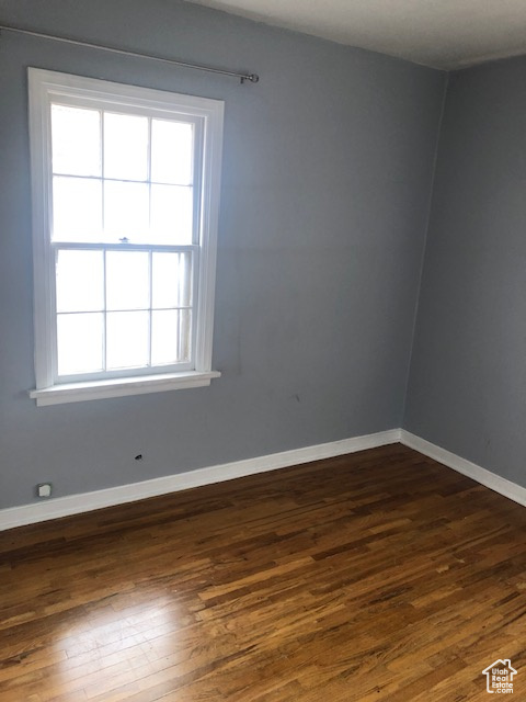 Spare room featuring dark wood-style floors and baseboards