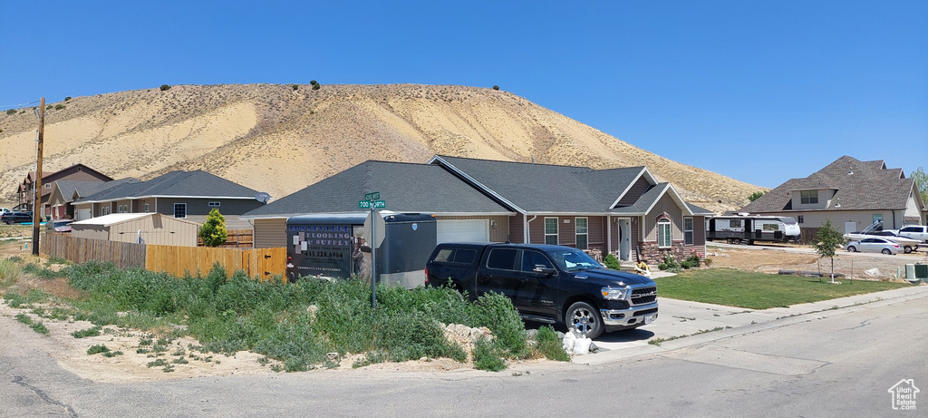 View of front facade featuring a garage, a mountain view, concrete driveway, and a residential view