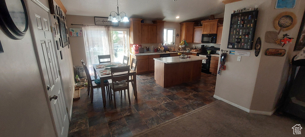 Kitchen with black appliances, a kitchen island, light countertops, a chandelier, and decorative light fixtures