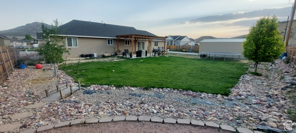 Back of house featuring a trampoline, a fenced backyard, a pergola, and a patio