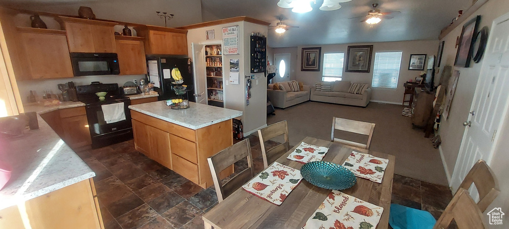 Kitchen featuring black appliances, ceiling fan, light countertops, open floor plan, and a kitchen island