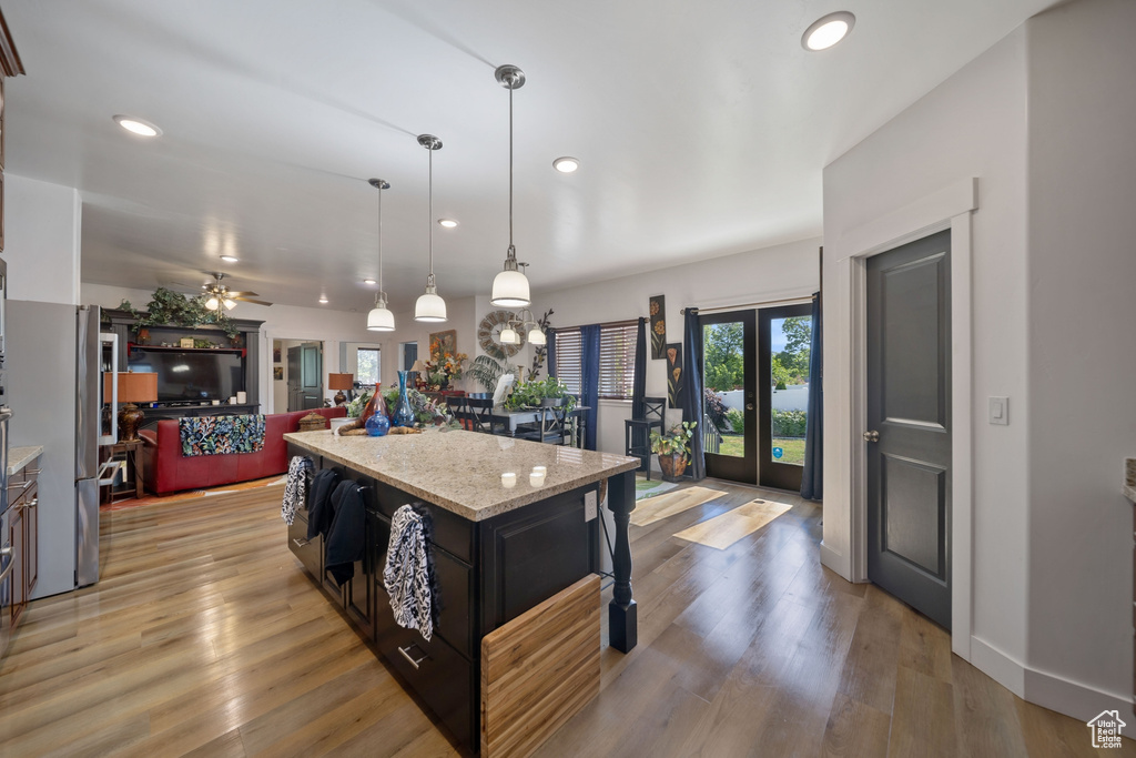 Kitchen featuring recessed lighting, open floor plan, a center island, freestanding refrigerator, and light stone counters