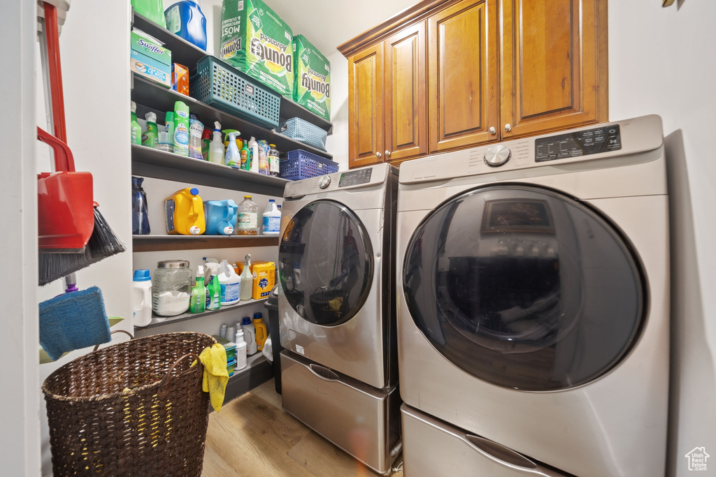 Laundry area featuring washer and dryer, wood finished floors, and cabinet space