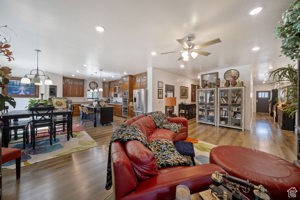 Living area featuring light wood-type flooring, a ceiling fan, and recessed lighting
