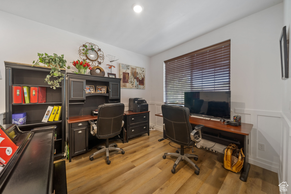 Office space with light wood-style floors, wainscoting, and a decorative wall