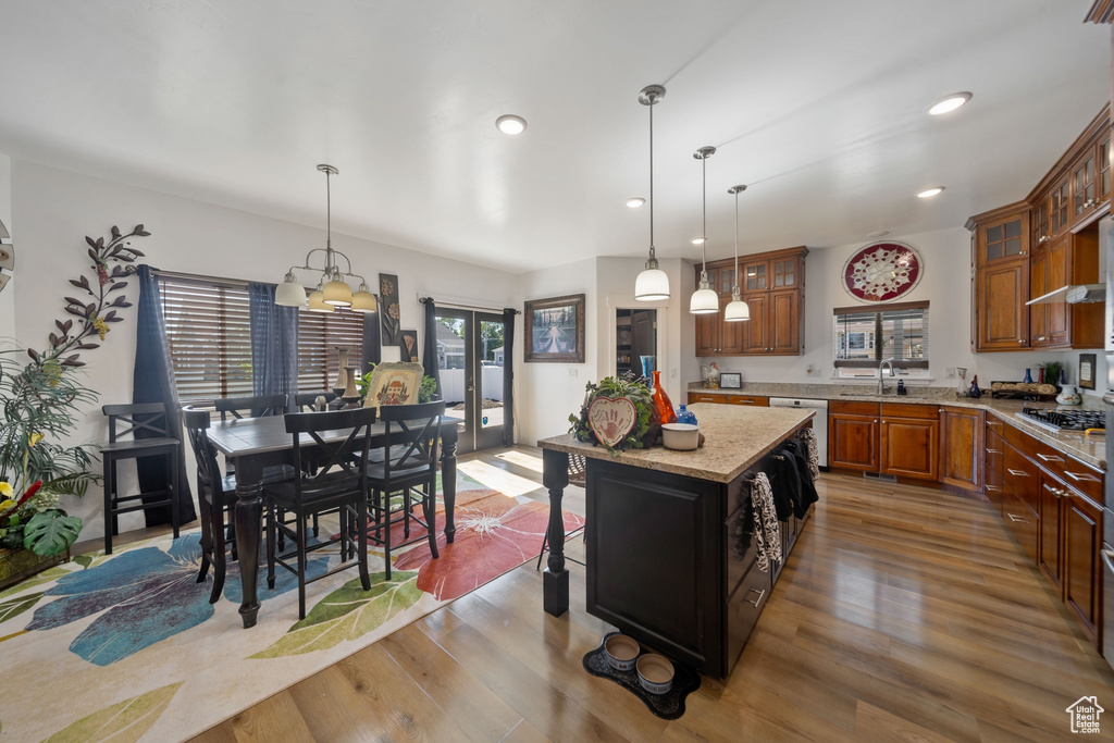 Kitchen featuring brown cabinets, glass insert cabinets, pendant lighting, light wood-type flooring, and recessed lighting
