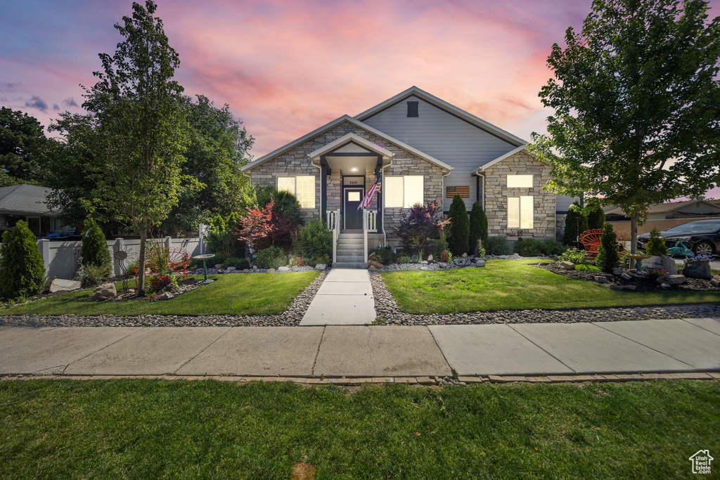 View of front of house featuring stone siding and a front lawn