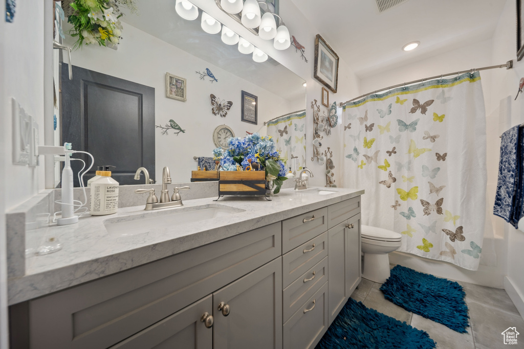 Full bathroom featuring double vanity, shower / bath combo with shower curtain, and tile patterned floors