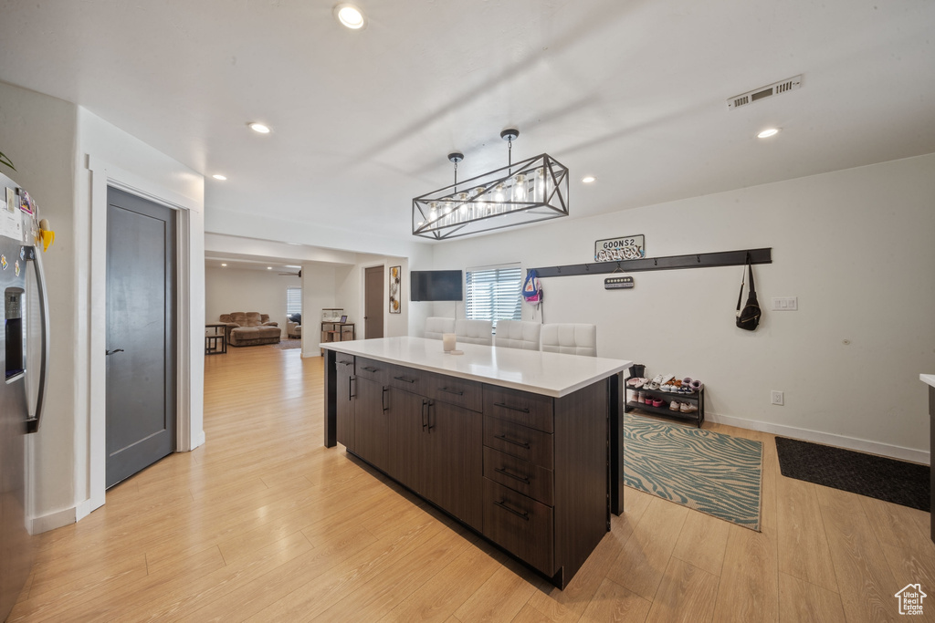 Kitchen with dark brown cabinets, a center island, light countertops, light wood-style floors, and recessed lighting