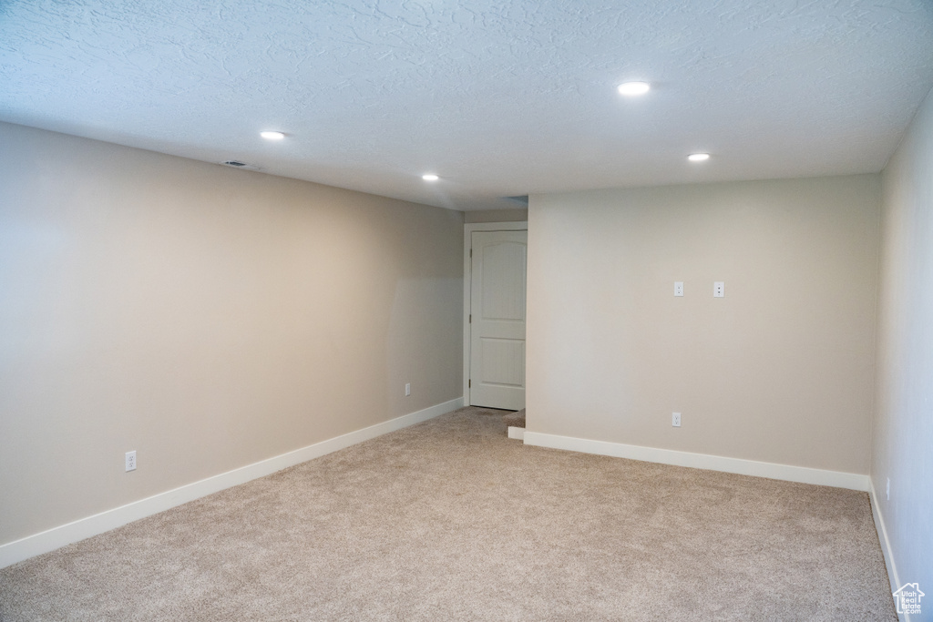 Spare room featuring light colored carpet, recessed lighting, and a textured ceiling