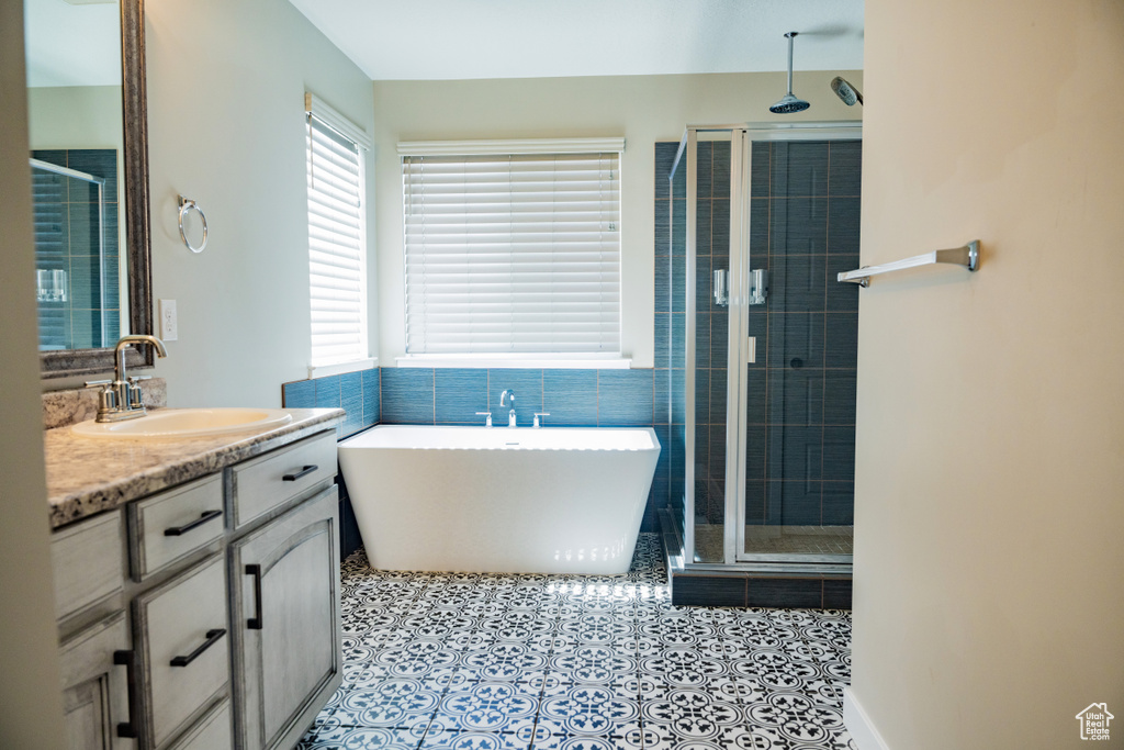 Full bathroom featuring a shower stall, vanity, a freestanding tub, and tile patterned flooring