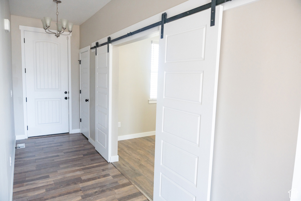 Foyer entrance featuring a barn door, wood finished floors, and a chandelier