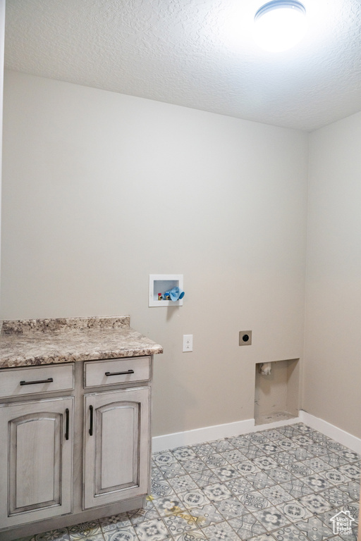 Washroom featuring electric dryer hookup, washer hookup, cabinet space, and a textured ceiling