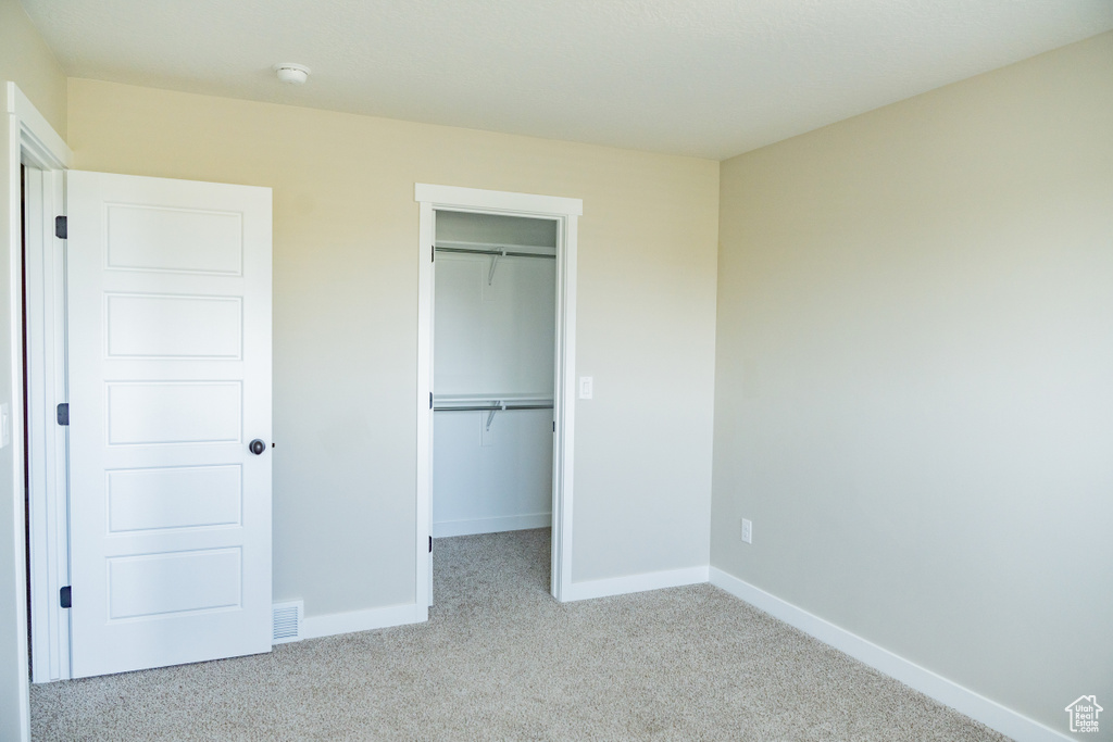 Unfurnished bedroom with carpet, a spacious closet, and a closet