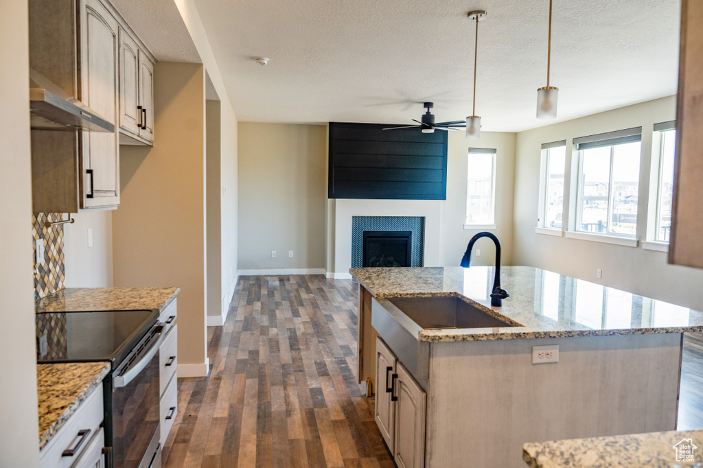 Kitchen featuring stainless steel electric range, ceiling fan, dark wood-type flooring, open floor plan, and a fireplace