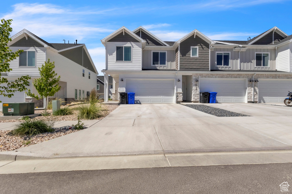 Multi unit property with a garage, stone siding, board and batten siding, and driveway