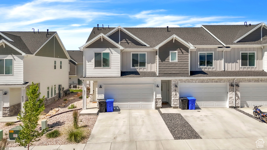 Multi unit property with board and batten siding, an attached garage, stone siding, a shingled roof, and concrete driveway