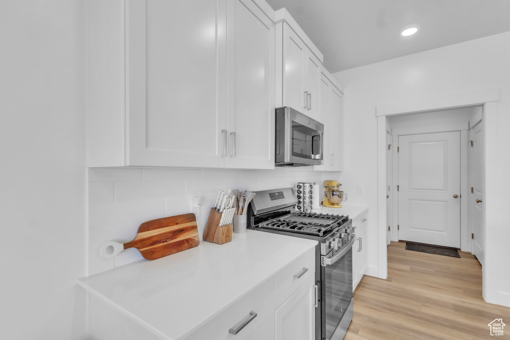 Kitchen featuring stainless steel appliances, white cabinets, decorative backsplash, and recessed lighting