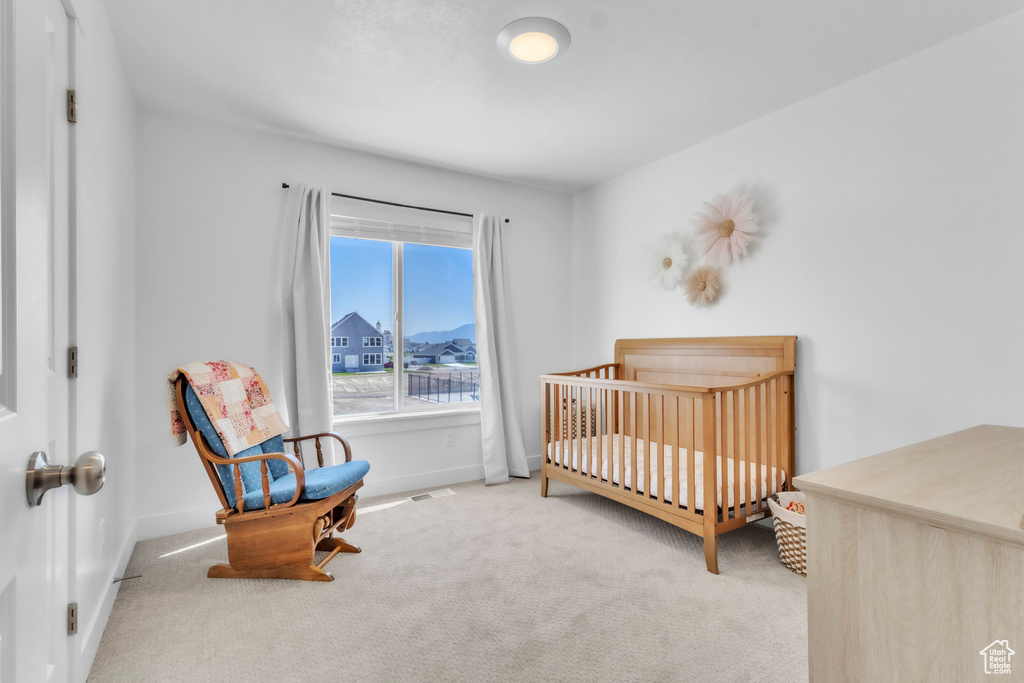 Carpeted bedroom featuring baseboards and a nursery area