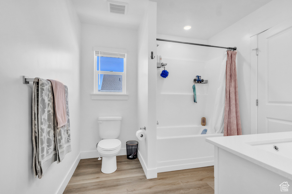 Full bathroom featuring shower / bath combination with curtain, wood finished floors, and vanity