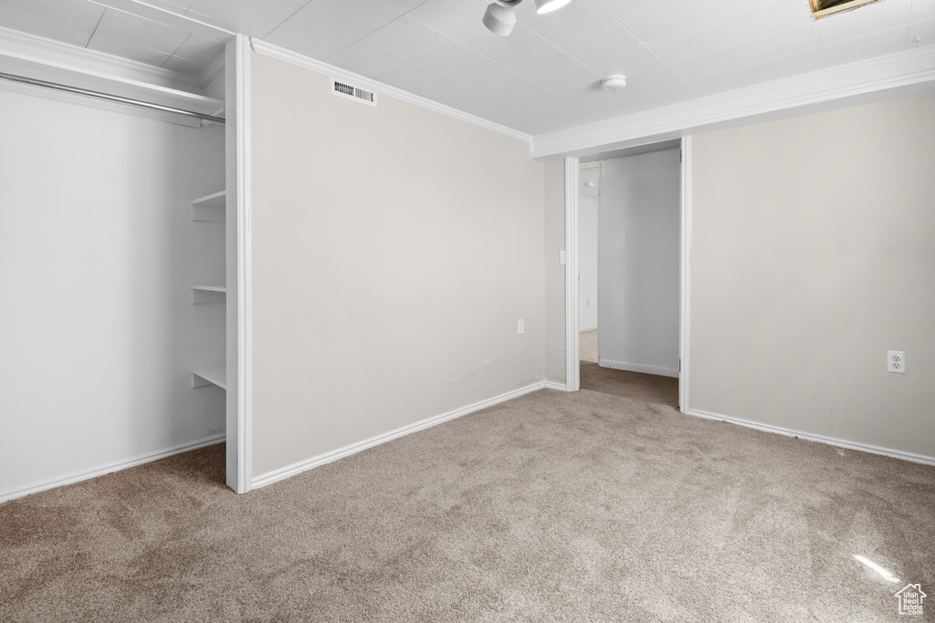 Unfurnished bedroom with crown molding, carpet, and a closet