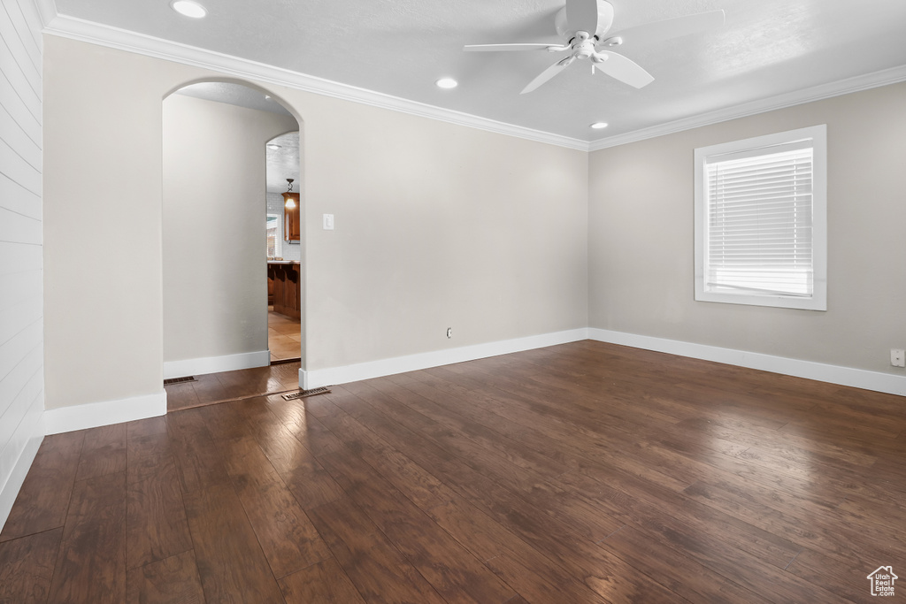 Spare room featuring arched walkways, ceiling fan, dark wood-style flooring, ornamental molding, and recessed lighting
