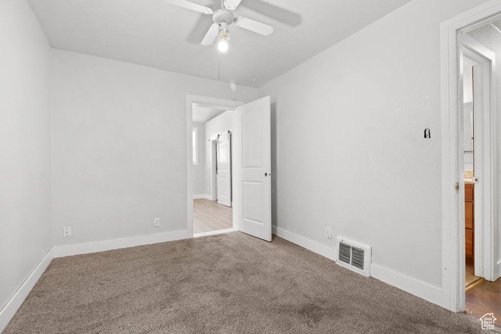 Carpeted empty room with ceiling fan and baseboards