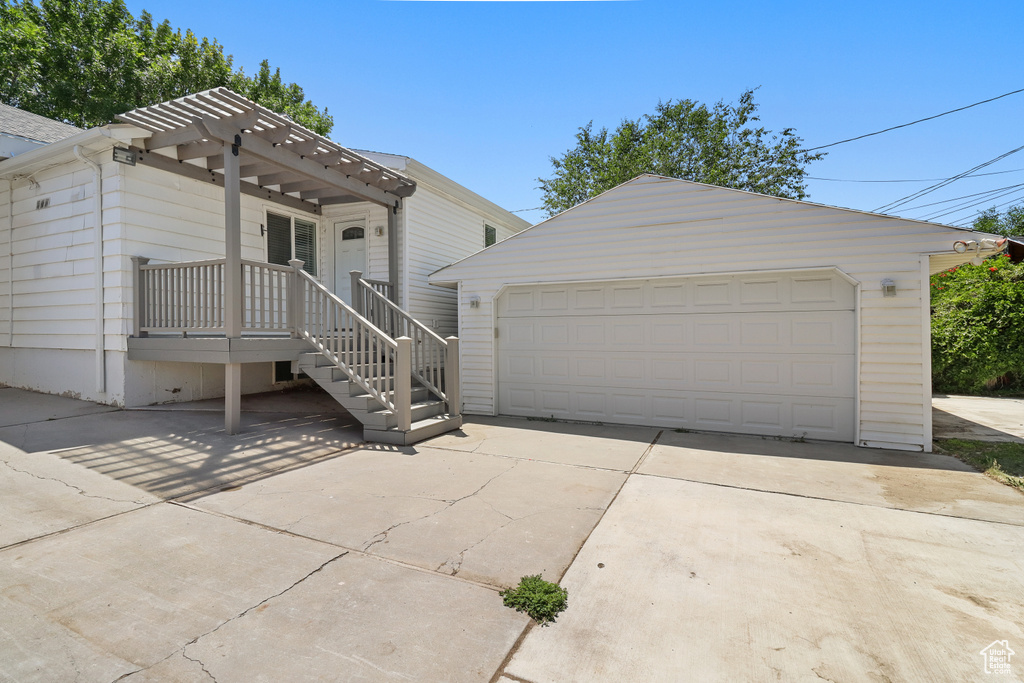 View of front of property with a detached garage, an outdoor structure, and a pergola