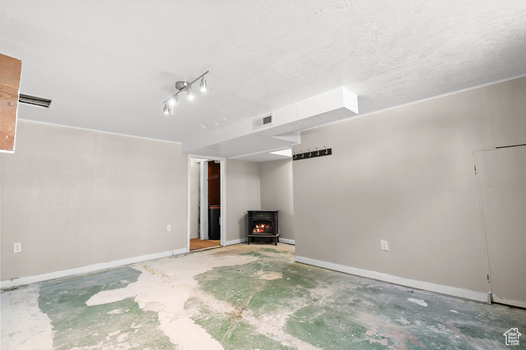 Unfurnished living room featuring a wood stove and concrete flooring