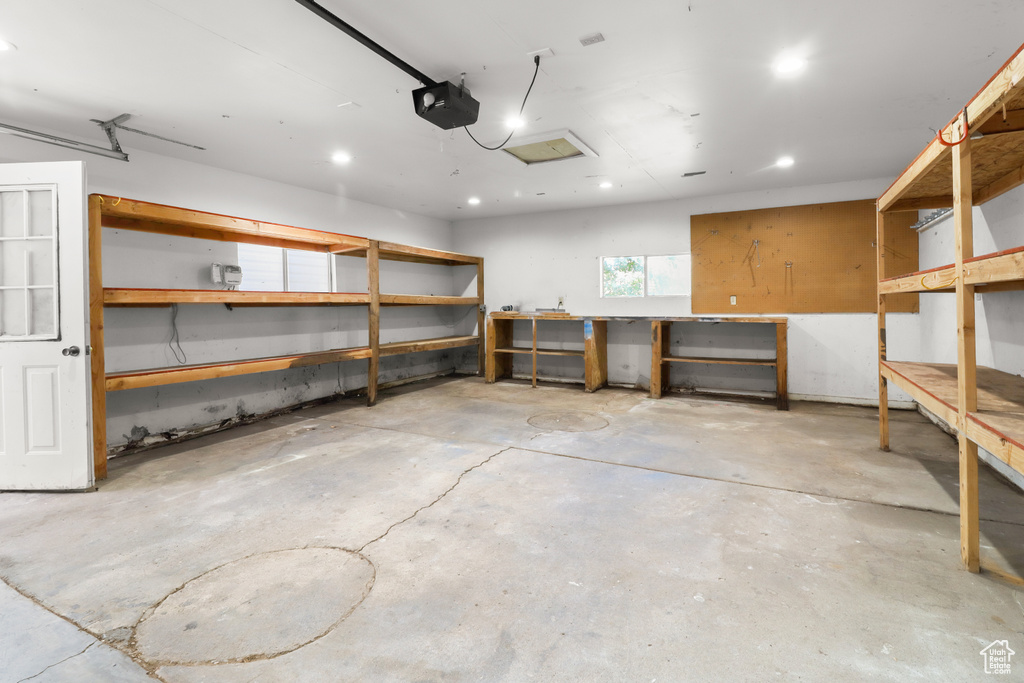 Garage featuring a workshop area, a garage door opener, and recessed lighting