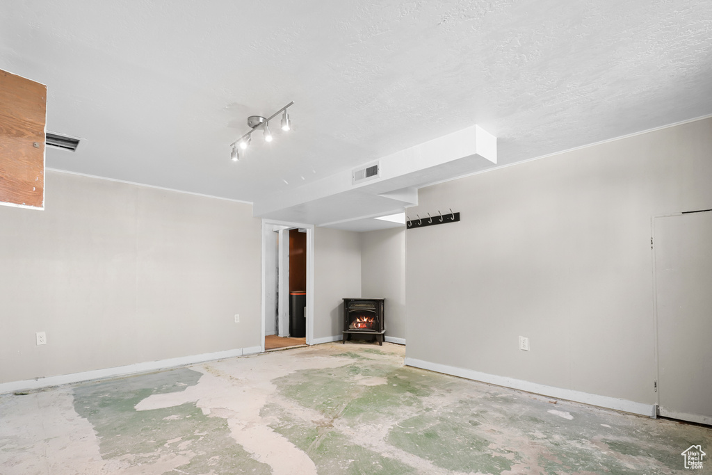 Unfurnished living room with a wood stove and unfinished concrete floors