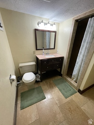 Full bath featuring a textured ceiling, vanity, a textured wall, and a stall shower