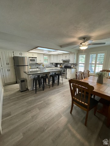 Dining area with a textured ceiling, healthy amount of natural light, light wood-style flooring, and ceiling fan