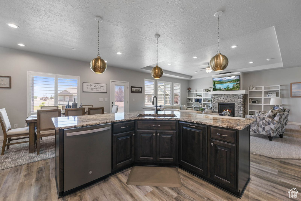 Kitchen with dishwasher, a textured ceiling, wood finished floors, a fireplace, and open floor plan