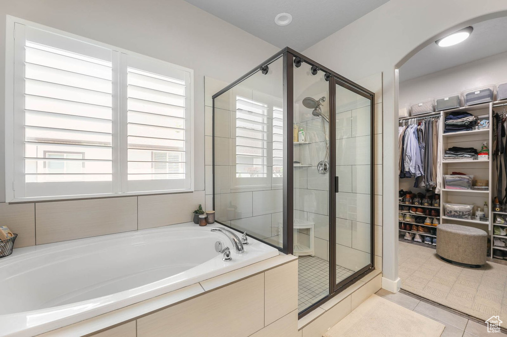 Full bath with a bath, a stall shower, a walk in closet, and tile patterned flooring