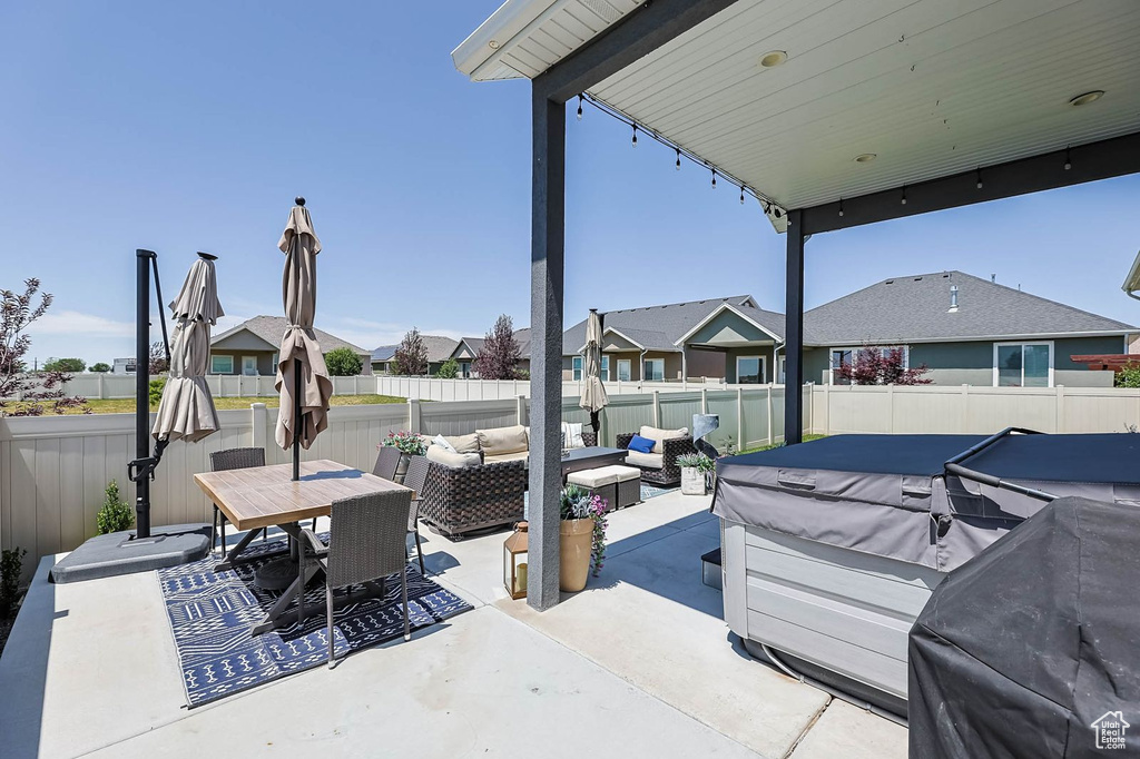 Fenced backyard featuring outdoor lounge area, a patio area, a residential view, a hot tub, and outdoor dining area