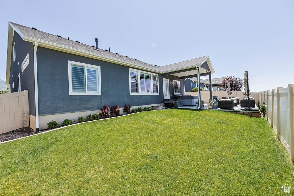 Back of property with outdoor lounge area, a hot tub, a fenced backyard, a patio, and stucco siding