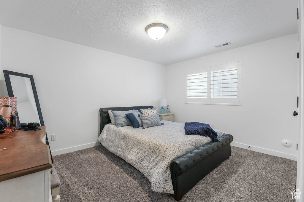 Bedroom featuring carpet flooring and a textured ceiling