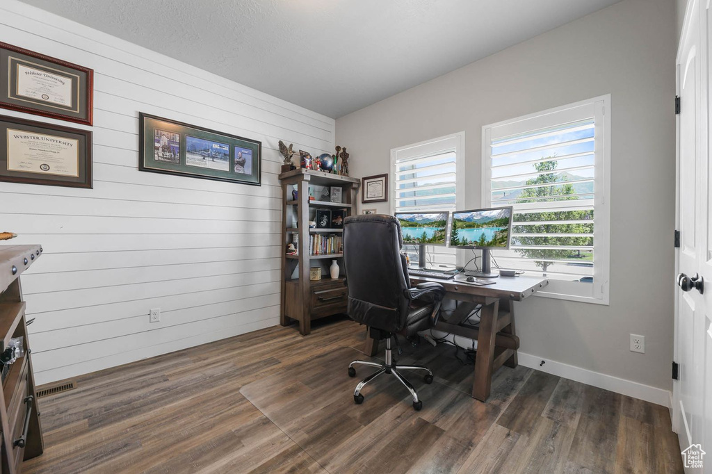 Office with healthy amount of natural light, wood walls, and wood finished floors