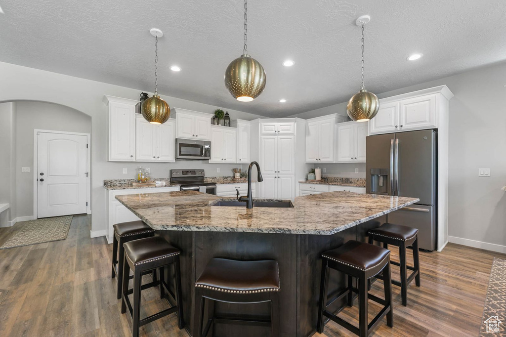 Kitchen featuring stainless steel appliances, dark wood-style floors, white cabinets, a spacious island, and recessed lighting