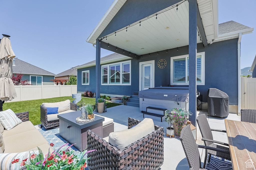 Fenced backyard featuring a hot tub, an outdoor hangout area, a patio, and a grill