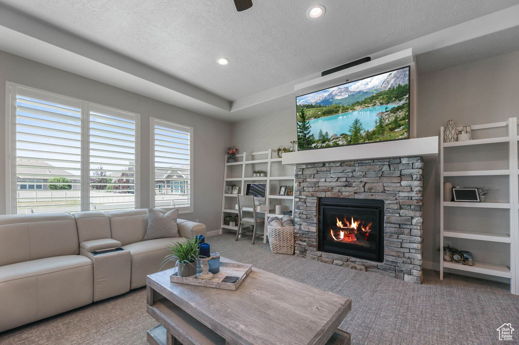 Living area featuring a textured ceiling, carpet floors, a fireplace, and recessed lighting