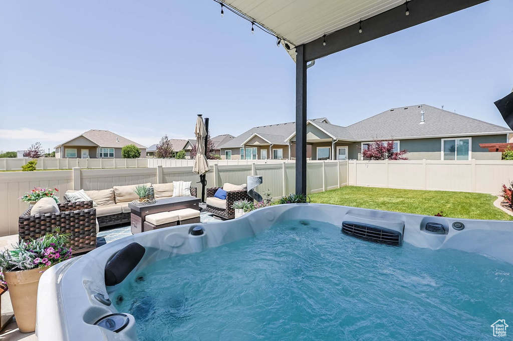 Fenced backyard featuring a hot tub, an outdoor hangout area, and a residential view